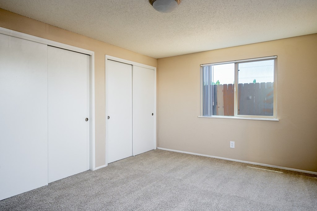an empty room with two closets and a window