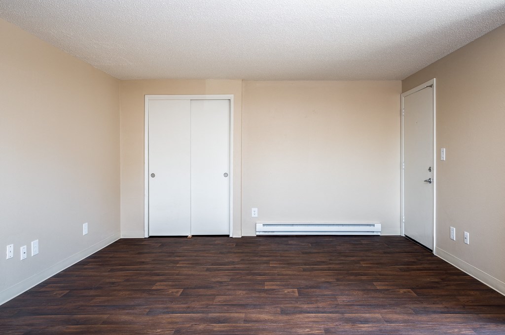 an empty living room with wood floors and white walls