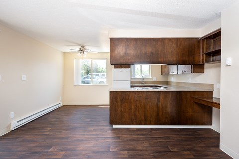 the view of a kitchen and living room with wood flooring and a ceiling fan