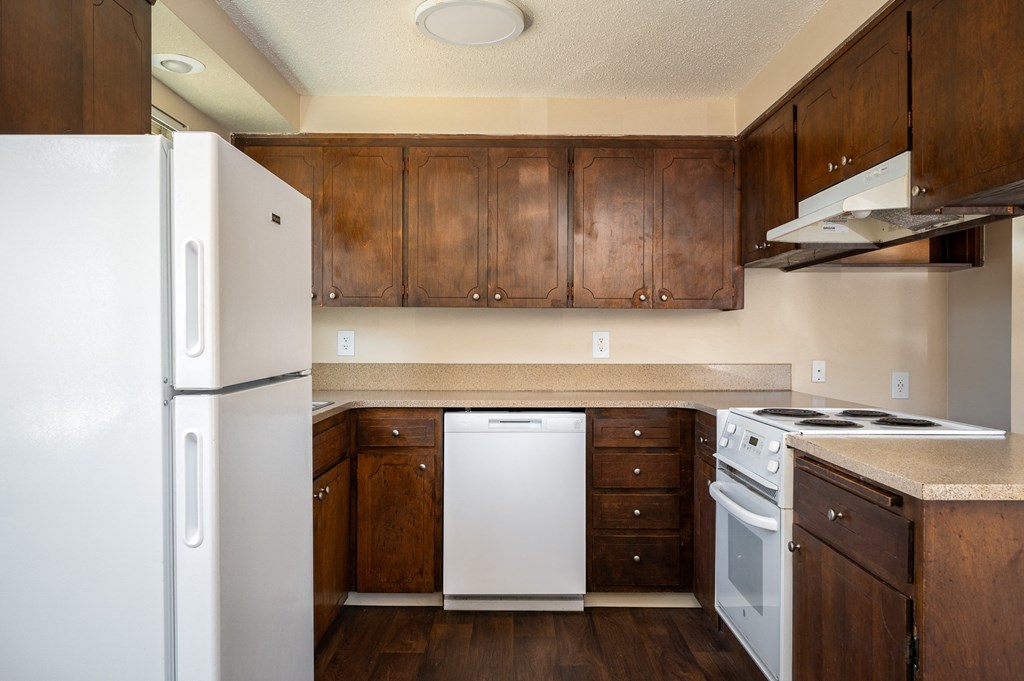 an empty kitchen with white appliances and wooden cabinets