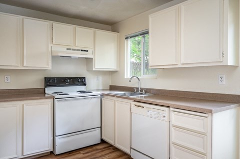 an empty kitchen with white appliances and white cabinets