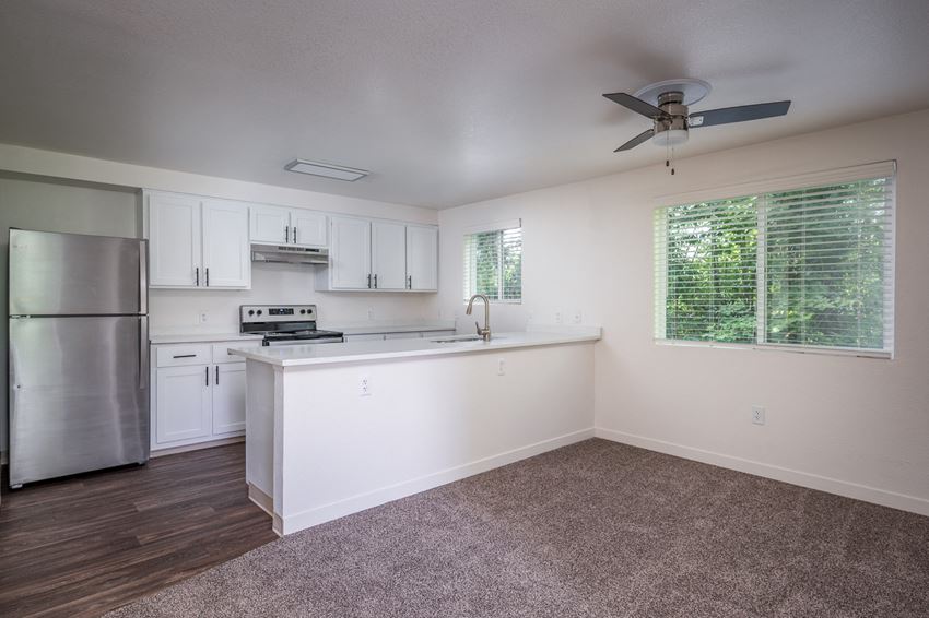 an empty kitchen with white cabinets and a stainless steel refrigerator