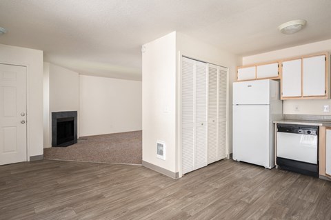 a living room with a fireplace and a kitchen with a stove and refrigerator