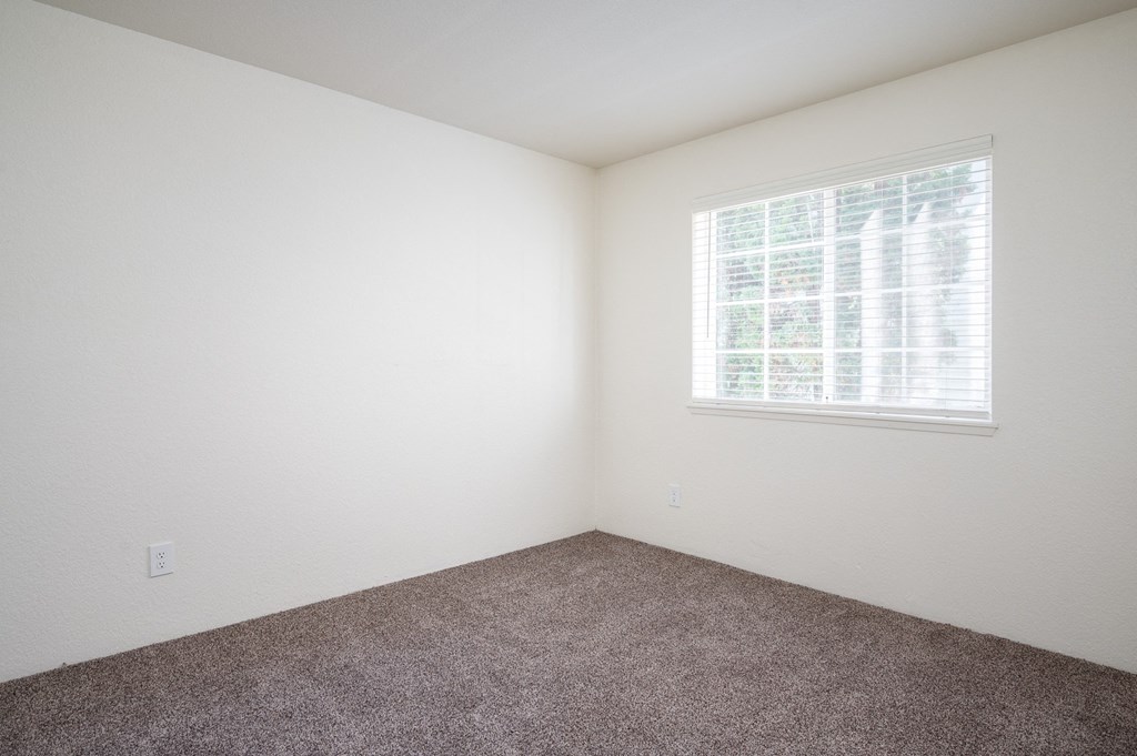 a bedroom with white walls and a window