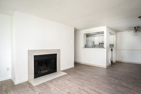 an empty living room with a fireplace and a ceiling fan