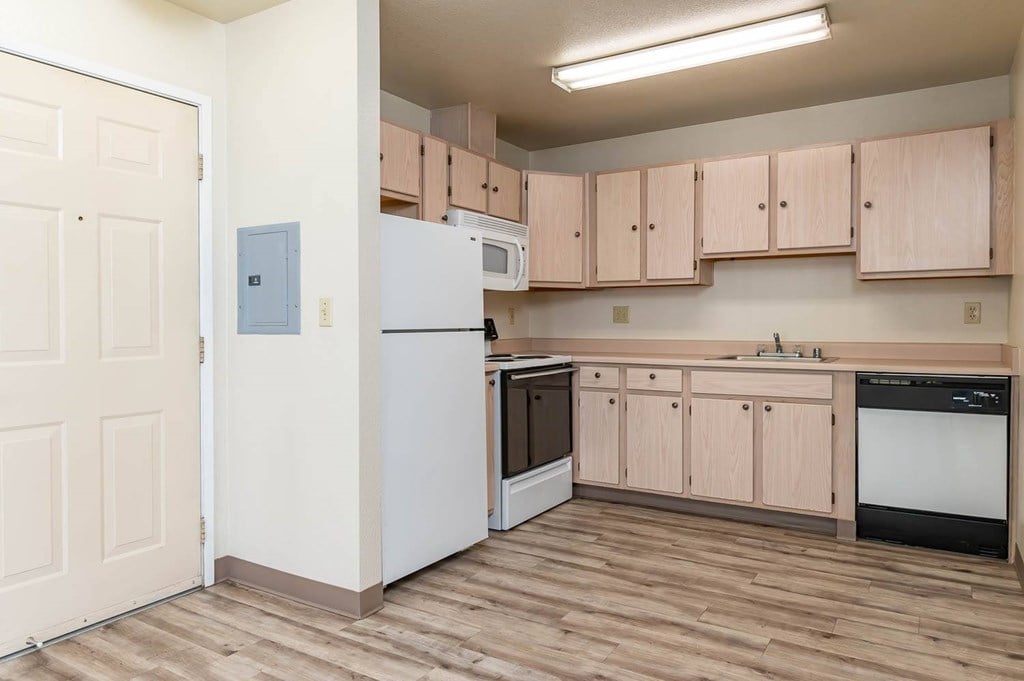 A kitchen with wooden floors and a white refrigerator.