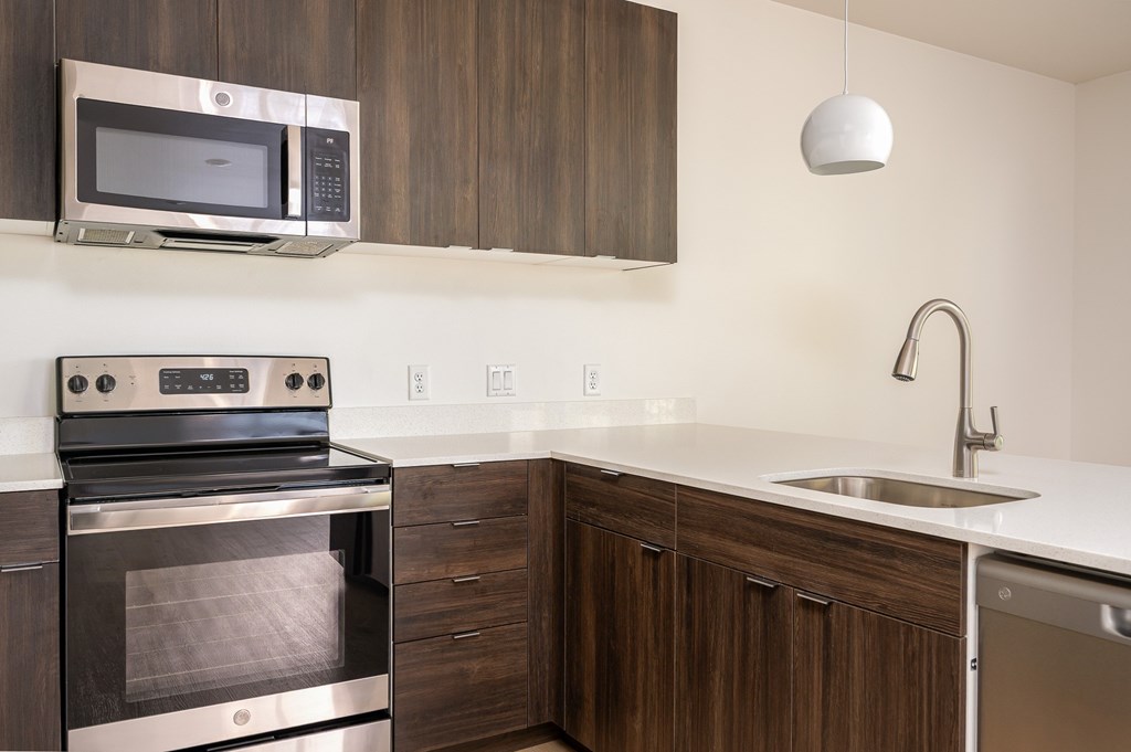 A modern kitchen with dark wood cabinets and stainless steel appliances.