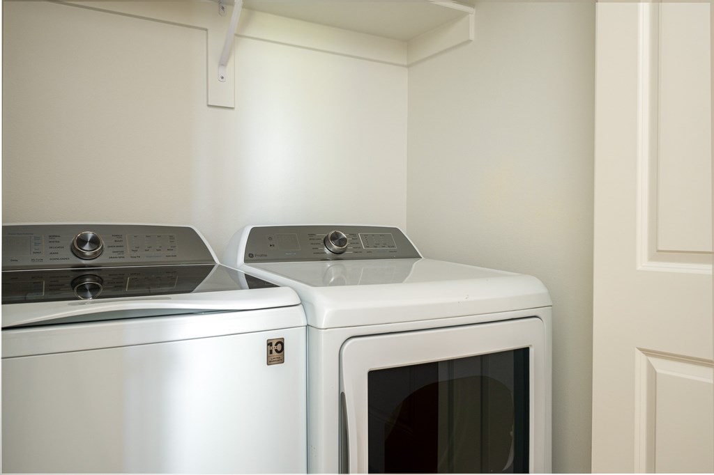 Two white appliances, a washing machine and a microwave, are stacked on top of each other.