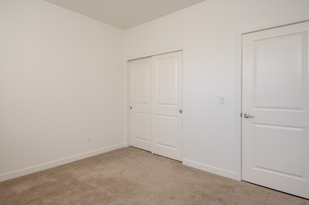 A room with two white closet doors and a carpeted floor.