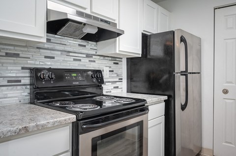 a kitchen with white cabinets and black appliances and a refrigerator