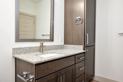 A bathroom with a sink, mirror, and cabinets.