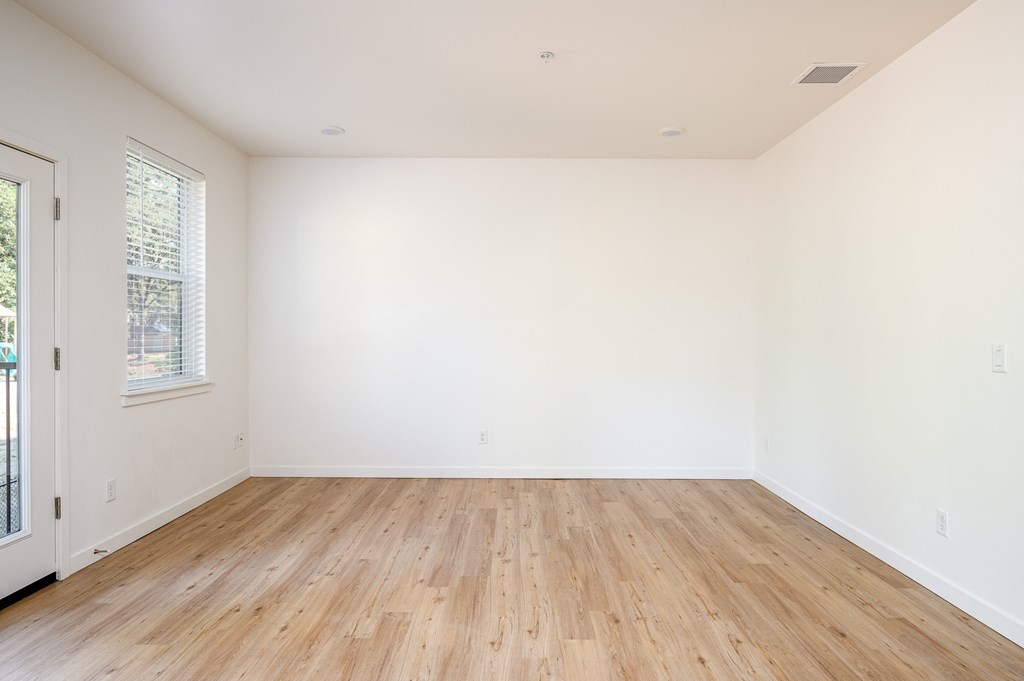 A room with wooden flooring and white walls.