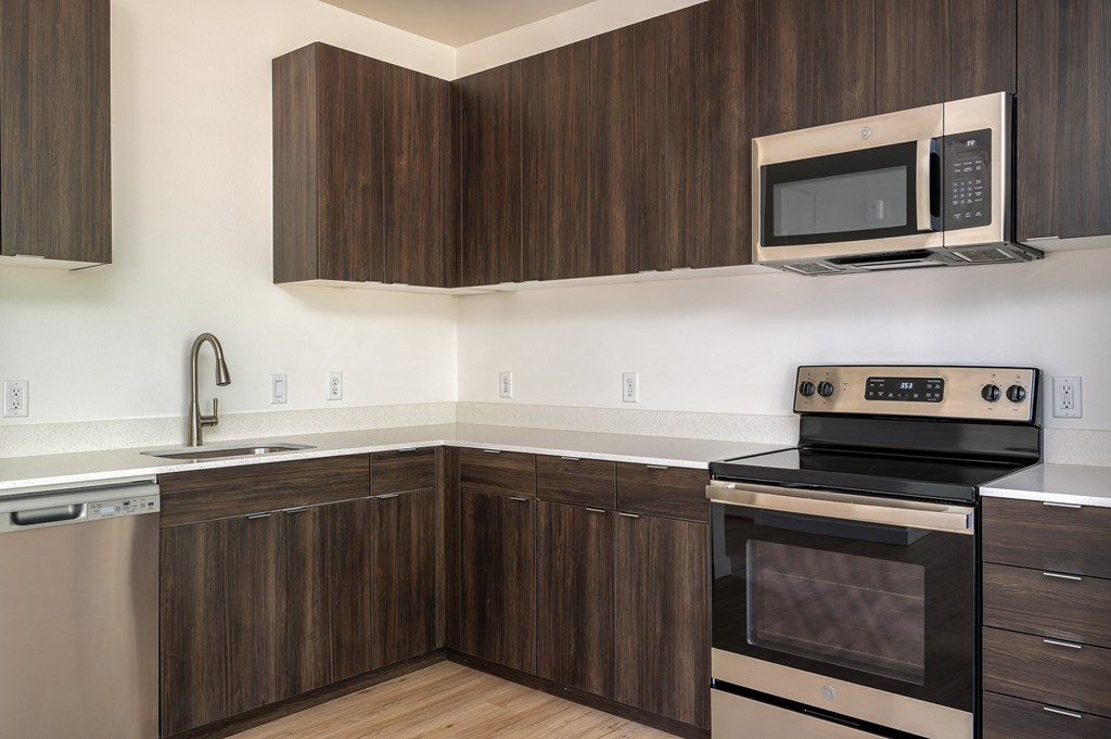 A modern kitchen with dark wood cabinets and stainless steel appliances.