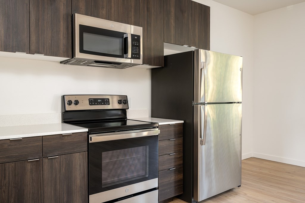 A modern kitchen with a stainless steel refrigerator, microwave, and oven.