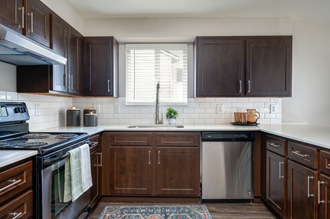 A kitchen with dark wood cabinets and a white tile backsplash.