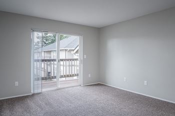 an empty living room with a large window and carpet