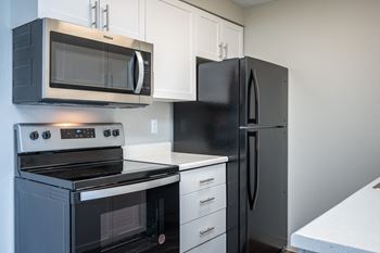 an empty kitchen with a stove refrigerator and microwave