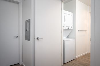 a white bathroom with a washing machine and a white door