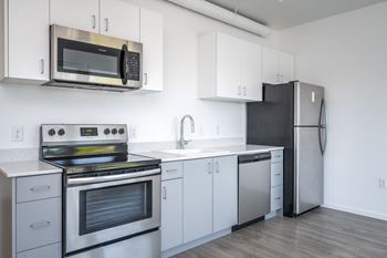 an empty kitchen with stainless steel appliances and white cabinets