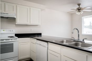 an empty kitchen with white cabinets and a stainless steel sink