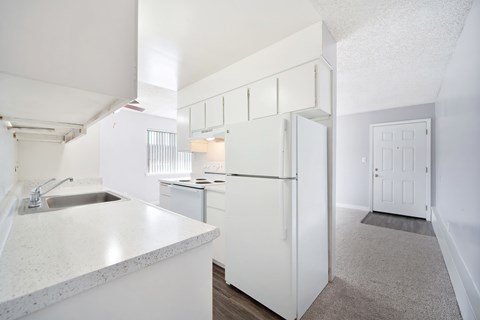 A kitchen with white cabinets and a white door.