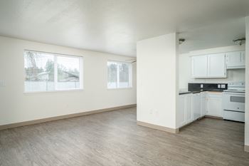 an empty kitchen and living room with white cabinets and white appliances