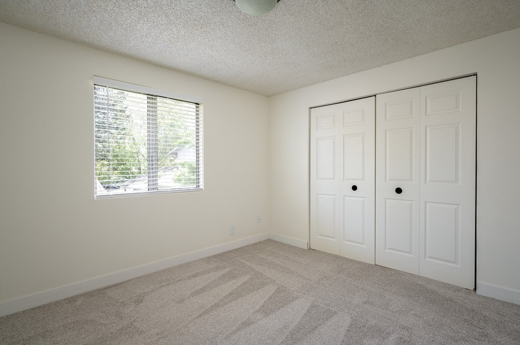 an empty bedroom with a window and two doors