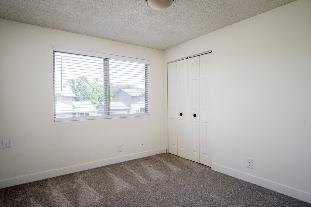an empty room with a window and a door and a closet
