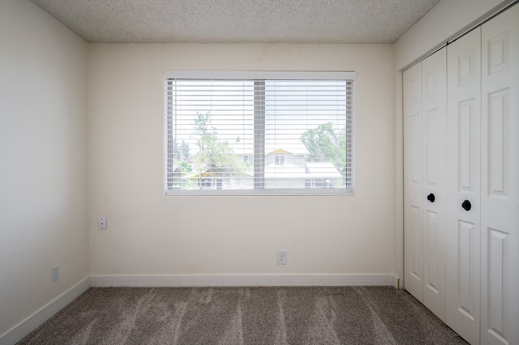 an empty bedroom with a large window and white doors