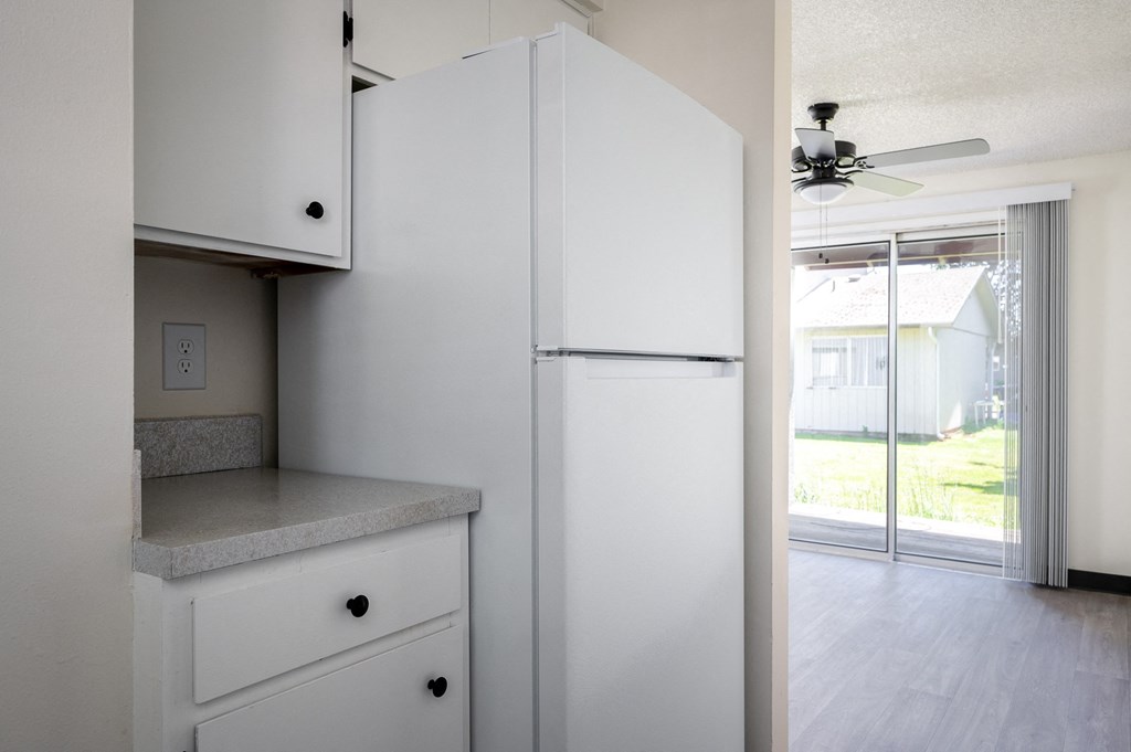 an empty kitchen with white cabinets and a ceiling fan