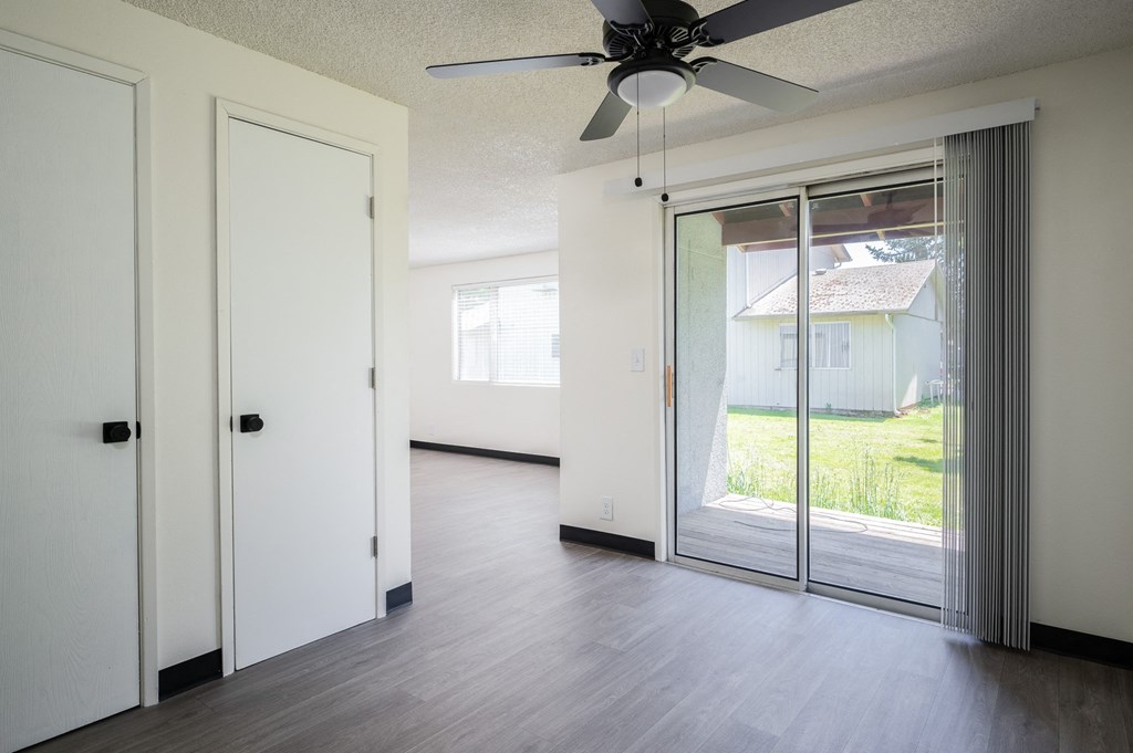 an empty living room with sliding glass doors and a ceiling fan