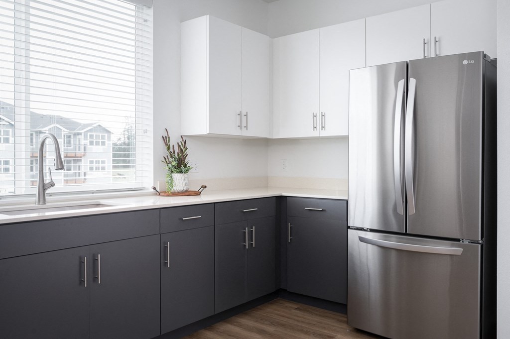 a kitchen with gray cabinets and a stainless steel refrigerator