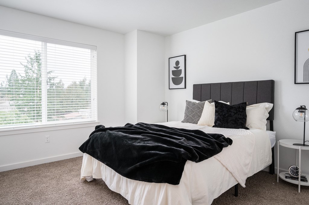 a bedroom with white walls and a large window with blinds