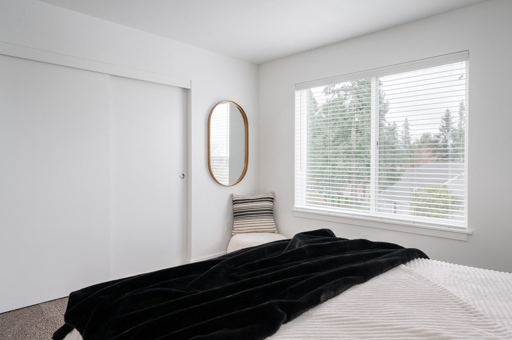 a bedroom with white walls, a large window and closet