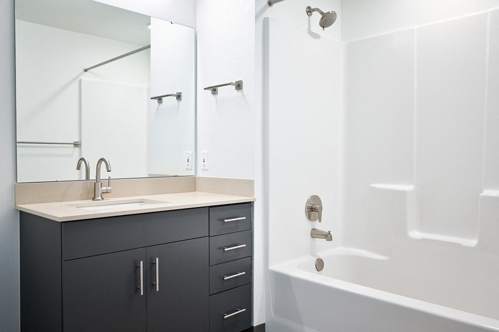 A white bathroom with a sink and a bathtub.