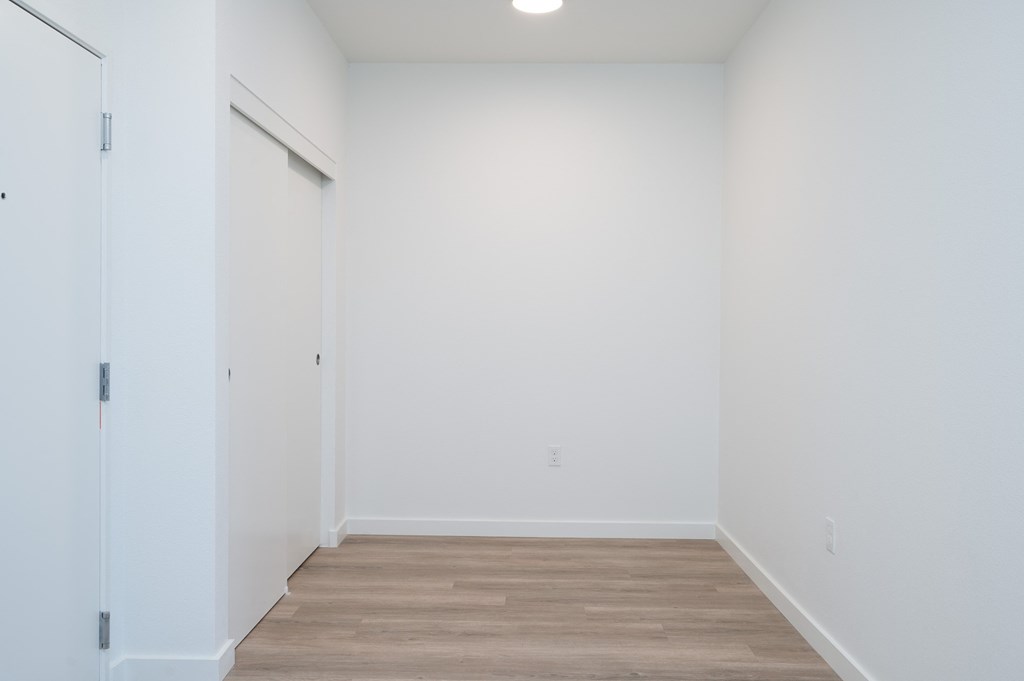 A room with a white door and wooden floor.
