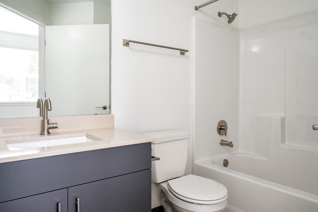 A white toilet sits in a bathroom with a sink and mirror.