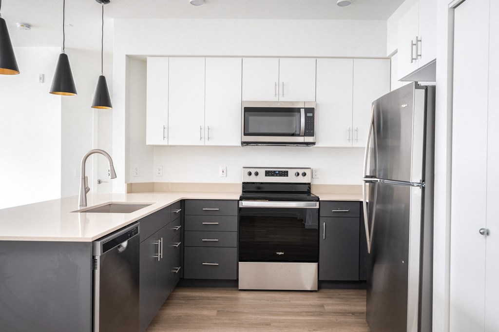 A modern kitchen with a refrigerator, oven, and microwave.
