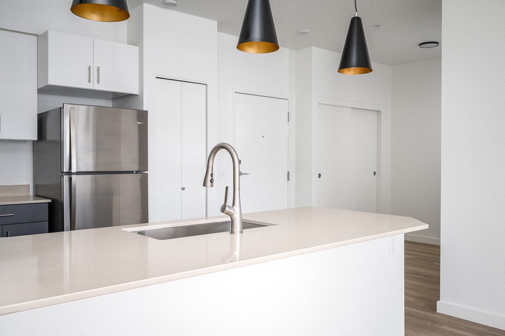 A modern kitchen with a stainless steel refrigerator and a white countertop.