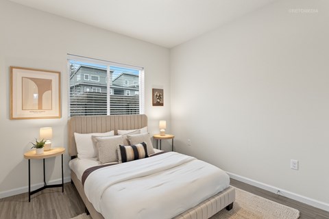 A bedroom with a large bed and a window with blinds.