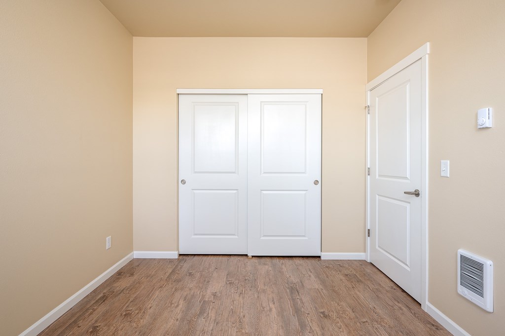 A room with two white doors and a vent on the wall.
