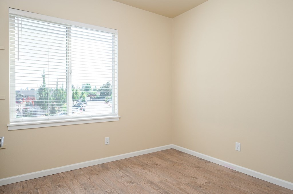 A room with a window and wooden flooring.