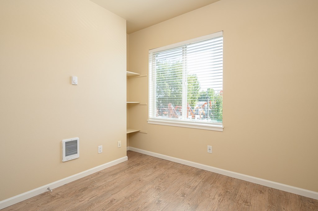A room with a window and a wooden floor.