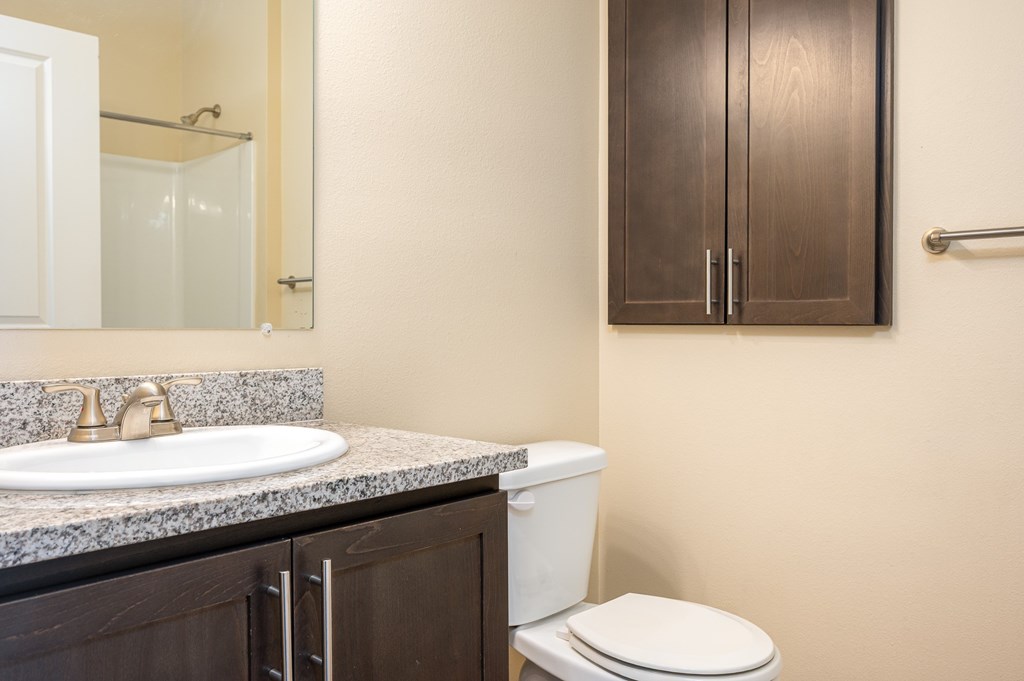 A bathroom with a toilet, sink, and mirror.