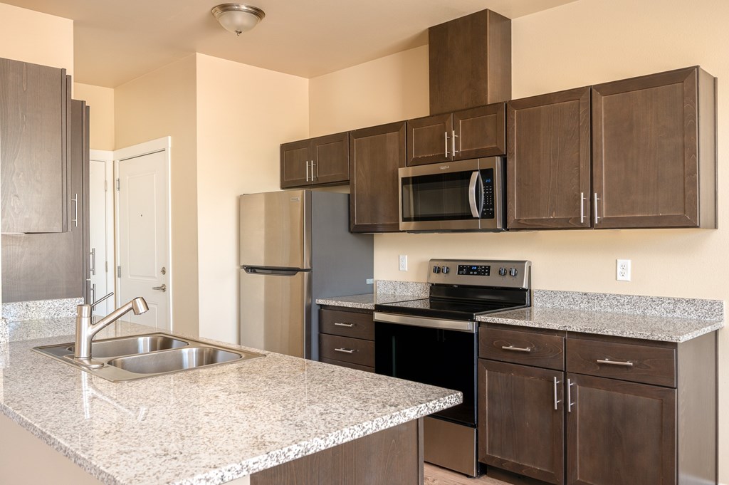 A kitchen with a granite countertop and stainless steel appliances.