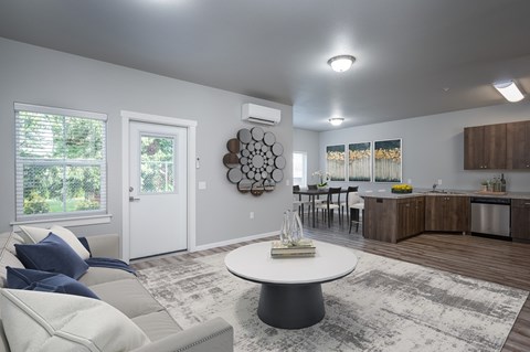 A modern living room with a white couch and a round table in the center.