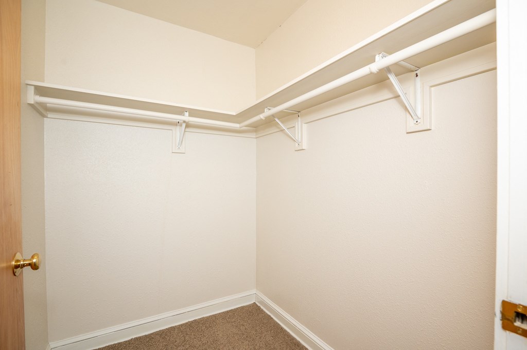 an empty closet with white walls and white hangers