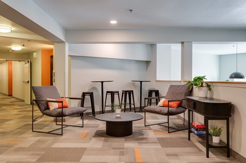 A modern lounge area with grey chairs and a round table.