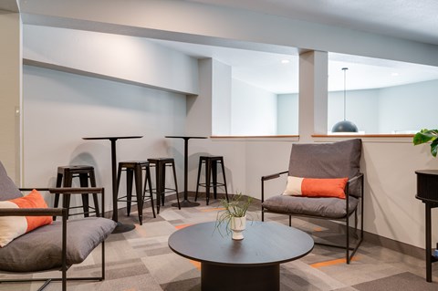 A modern living room with a grey sofa, a black coffee table, and a grey armchair.
