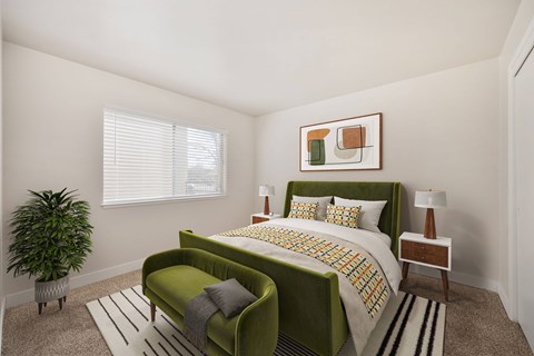 A bedroom with a green bed and a potted plant.